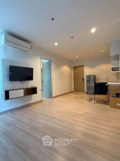 Spacious modern living room with sleek flooring and wall-mounted TV, perfect for urban living.
