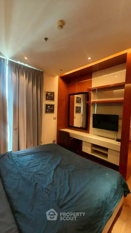Modern bedroom with stylish decor and built-in TV unit, perfect for urban living.