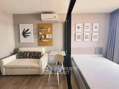 Modern studio apartment with stylish decor, featuring a cozy sofa, bed, and workspace with wall art.
