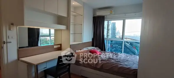 Cozy bedroom with city view, built-in desk, and ample storage in modern apartment.