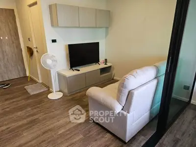 Cozy living room with modern decor and wooden flooring, featuring a comfortable sofa and sleek TV setup.
