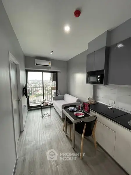Modern apartment with open kitchen and cozy living area, featuring a balcony with city views.