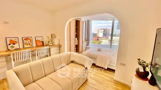Bright modern living room with cozy sofa and stylish decor, featuring a view into a chic bedroom.