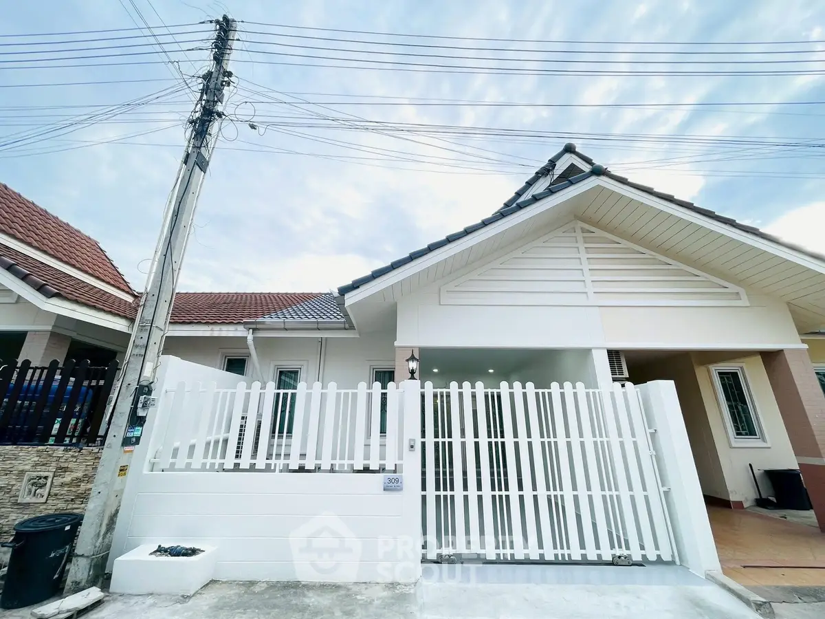 Charming single-story house with white picket fence and tiled roof in a serene neighborhood.