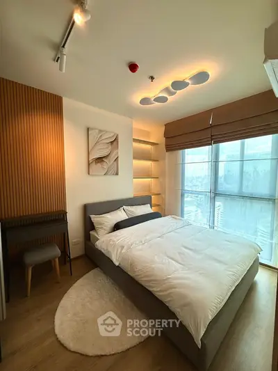 Modern bedroom with large window and stylish lighting in a high-rise apartment.