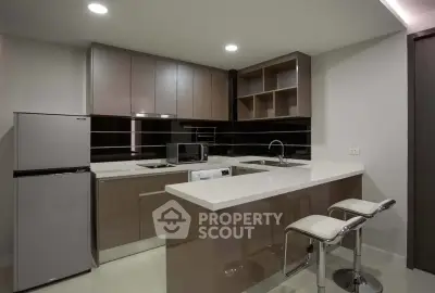 Modern kitchen with sleek cabinetry, island seating, and stainless steel appliances in a stylish apartment.