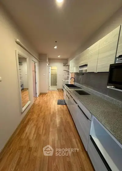 Modern kitchen with sleek cabinetry and wooden flooring in a stylish apartment.