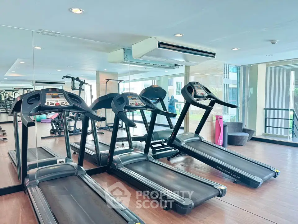Modern gym with treadmills and large mirrors in a luxury apartment building.