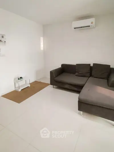 Modern living room with sleek gray sectional sofa and air conditioning unit, perfect for relaxation.