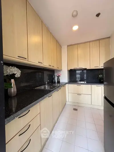 Modern kitchen with sleek cabinetry and granite countertops in a cozy apartment.