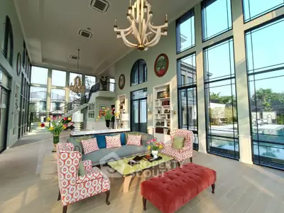 Luxurious living room with high ceilings, large windows, and elegant decor overlooking a scenic garden view.