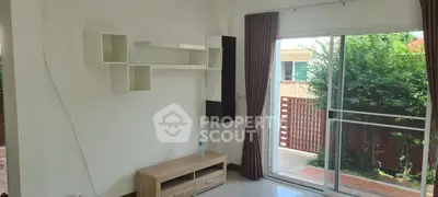 Bright living room with modern shelving and sliding glass doors to garden.