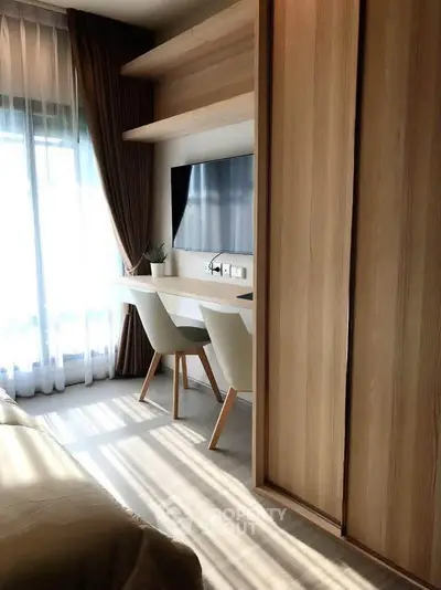 Modern bedroom with built-in desk and TV, featuring natural light and elegant decor.