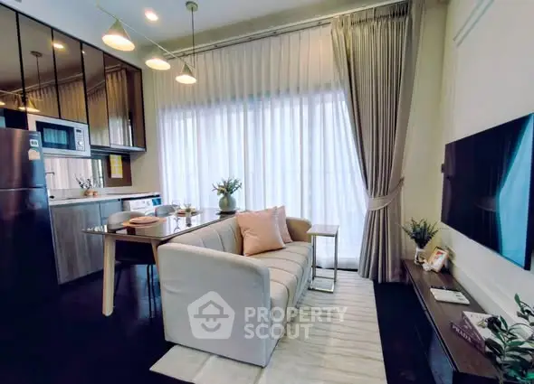 Modern living room with open kitchen, stylish decor, and natural light through large windows.