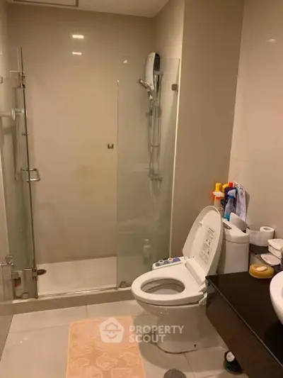 Modern bathroom with glass shower and toilet in sleek design.