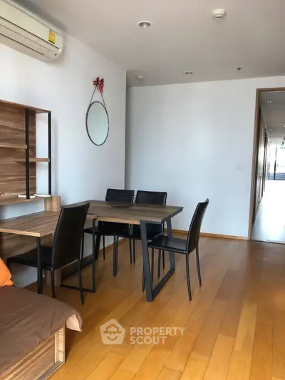 Modern dining area with wooden flooring and sleek furniture in a well-lit apartment.