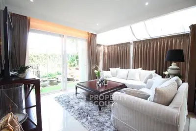 Elegant living room with large windows and plush seating, overlooking a serene garden.