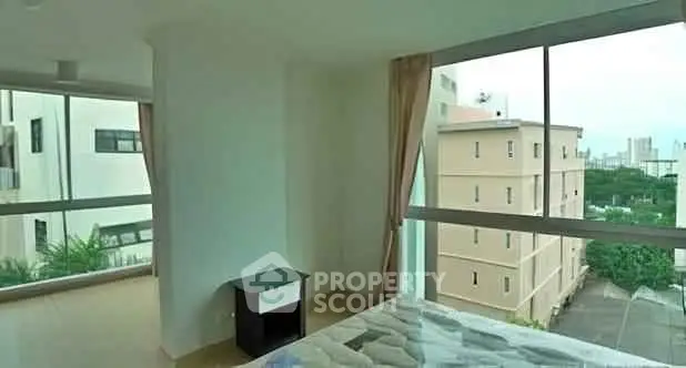 Spacious bedroom with large windows offering a stunning city view, perfect for urban living.
