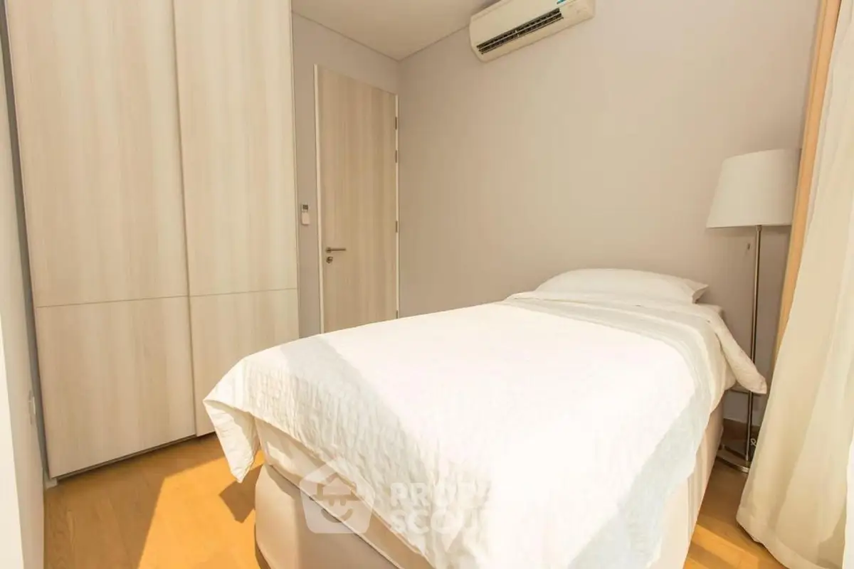 Cozy minimalist bedroom with natural light and modern furnishings.