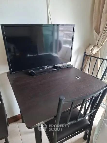 Cozy dining area with TV setup on a dark wooden table, perfect for small apartments.