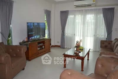 Spacious living room with elegant furniture and large TV, perfect for relaxation.