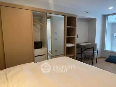 Modern bedroom with built-in wardrobe and study desk, featuring minimalist design and natural light.
