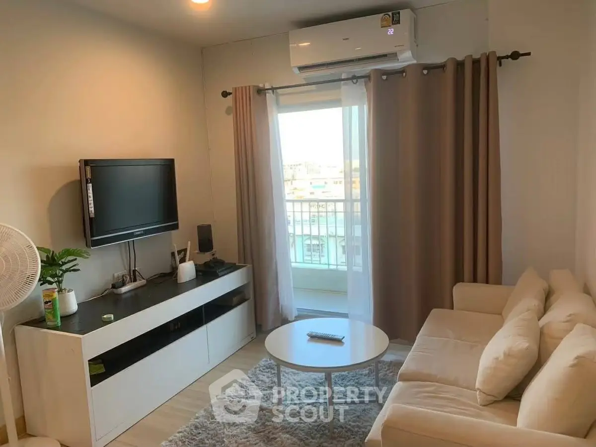 Cozy living room with modern decor, featuring a comfortable sofa, flat-screen TV, and air conditioning.