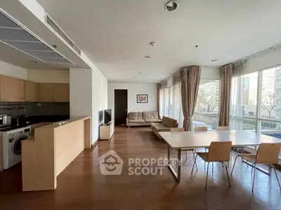 Spacious open-plan living room with modern kitchen and dining area, featuring large windows and natural light.