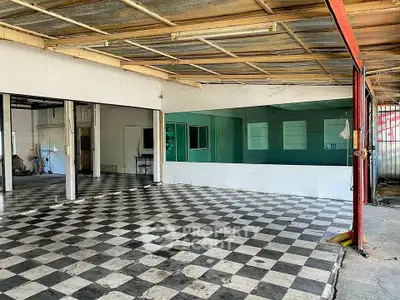 Spacious industrial space with checkered flooring and large windows, ideal for commercial use.