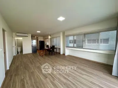Spacious open-plan living room with modern flooring and large windows in a contemporary apartment.
