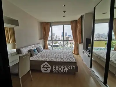 Spacious bedroom with city view and modern furnishings in a high-rise apartment.