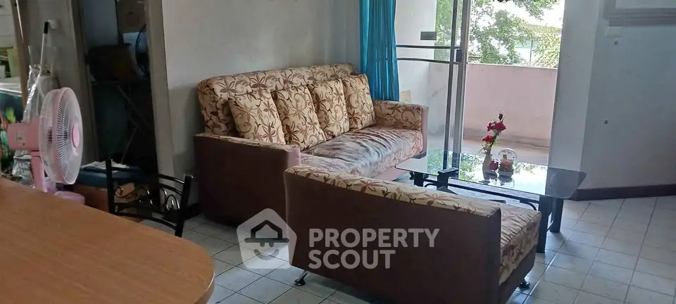 Cozy living room with floral sofa and balcony view, perfect for relaxation.