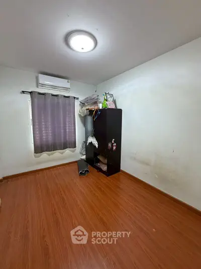 Cozy bedroom with wooden flooring and air conditioning, perfect for a comfortable living space.