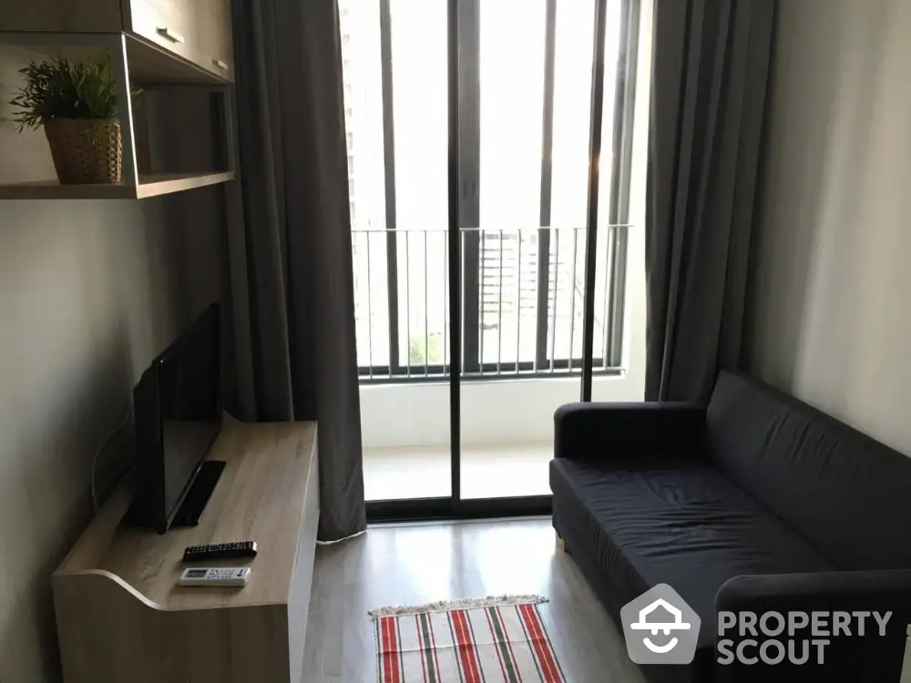 Cozy living room with modern sofa and TV, featuring a balcony view.