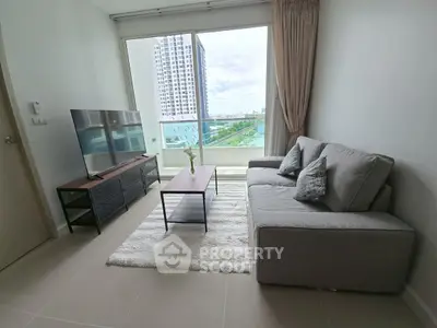 Modern living room with large window and city view, featuring a sleek sofa and flat-screen TV.