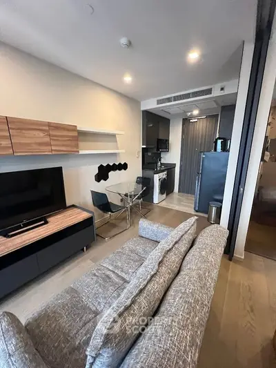 Modern living room with open kitchen layout, featuring stylish furniture and sleek appliances.