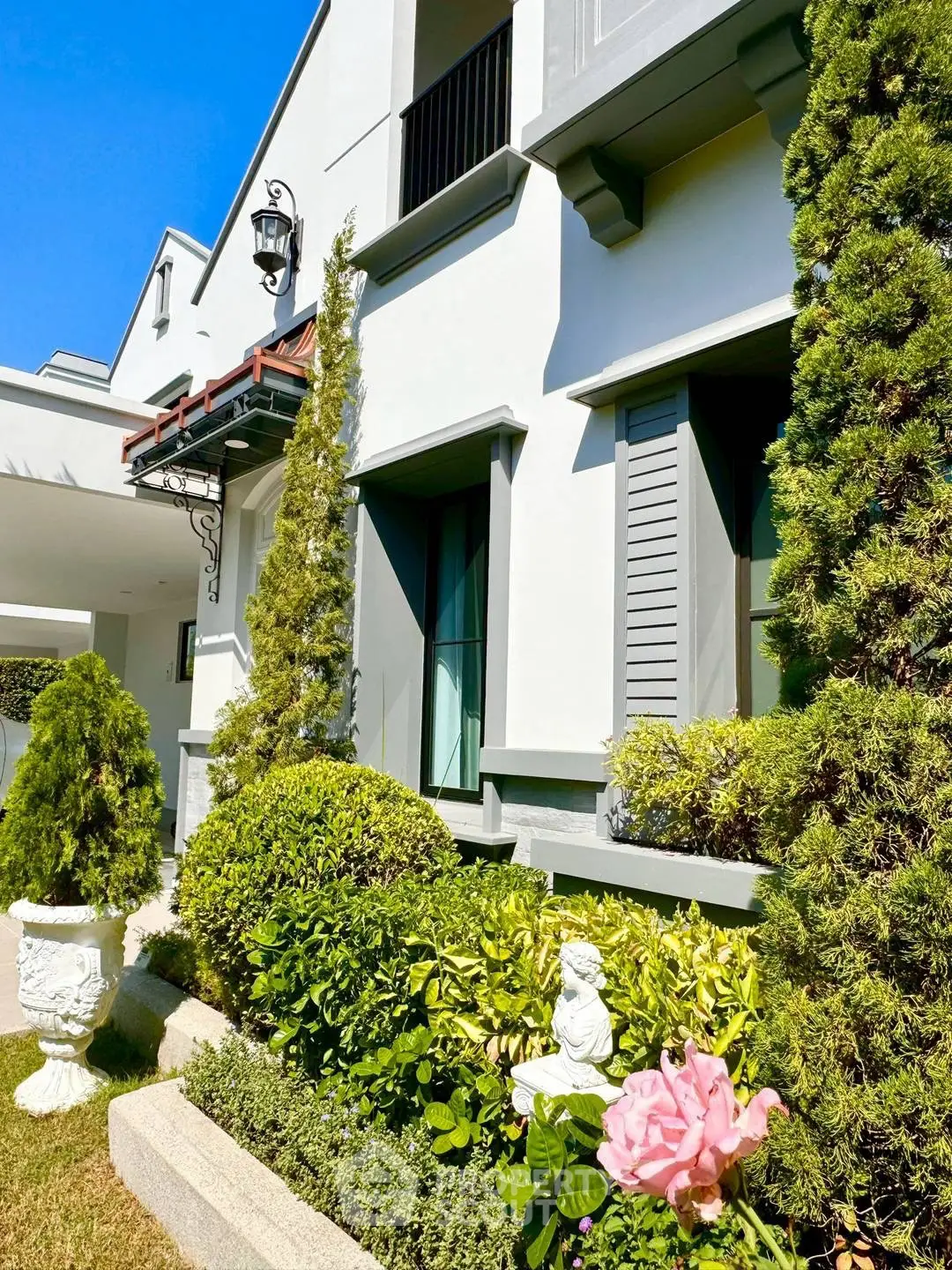 Charming residential building exterior with lush garden and elegant architectural details.