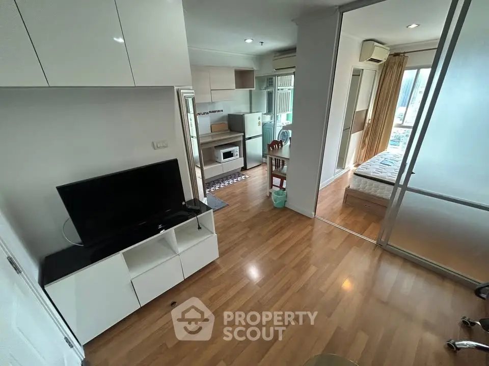 Modern apartment interior with open layout, featuring a cozy living area, compact kitchen, and bright bedroom.