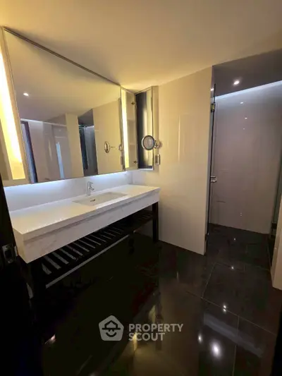 Modern bathroom with sleek design and large mirror, featuring elegant lighting and spacious layout.