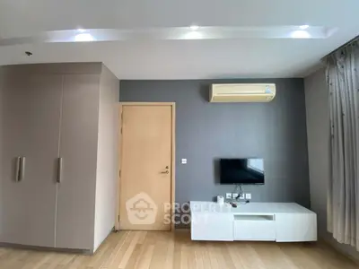 Modern living room with sleek design, featuring built-in wardrobe, wall-mounted TV, and air conditioning.