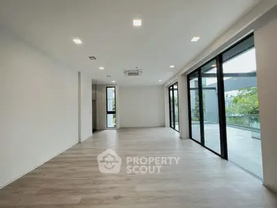 Spacious modern living room with large windows and sleek flooring, offering abundant natural light and outdoor views.