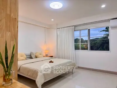 Spacious bedroom with large window and cozy decor in modern apartment