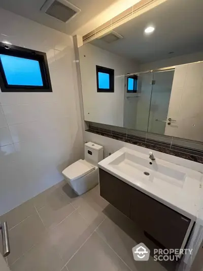 Modern bathroom with sleek fixtures, large mirror, and neutral color palette, perfect for a contemporary home or apartment.