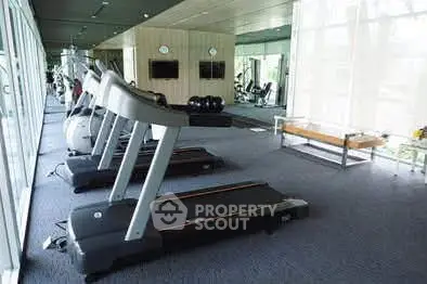 Modern gym with state-of-the-art equipment and large windows offering natural light.