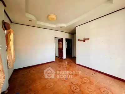 Spacious empty room with tiled floor and ceiling light, ready for customization.