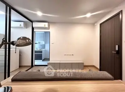 Modern living room with sleek design and open kitchen view, featuring stylish lighting and contemporary furniture.