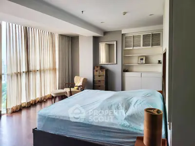 Spacious bedroom with large windows and elegant furnishings in modern apartment.