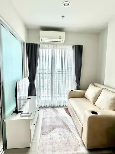 Cozy living room with modern sofa, TV, and large window for natural light.