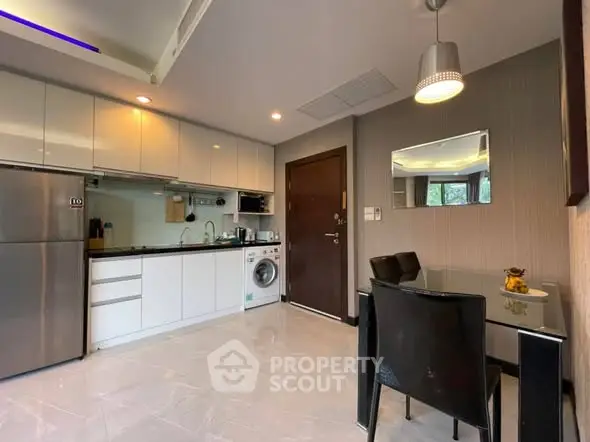 Modern kitchen with sleek cabinetry, stainless steel appliances, and dining area in stylish apartment.