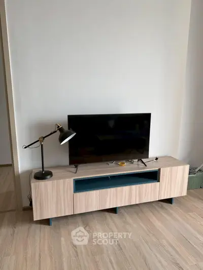 Modern living room with stylish TV stand and lamp on wooden flooring.